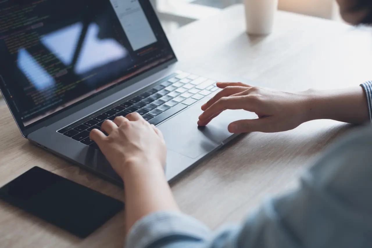 Person tippt auf der Tastatur eines Laptops